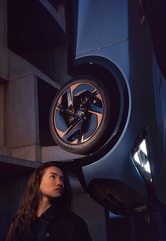 Woman standing in front of Cupra Car hanging from ceiling in stylistic way
