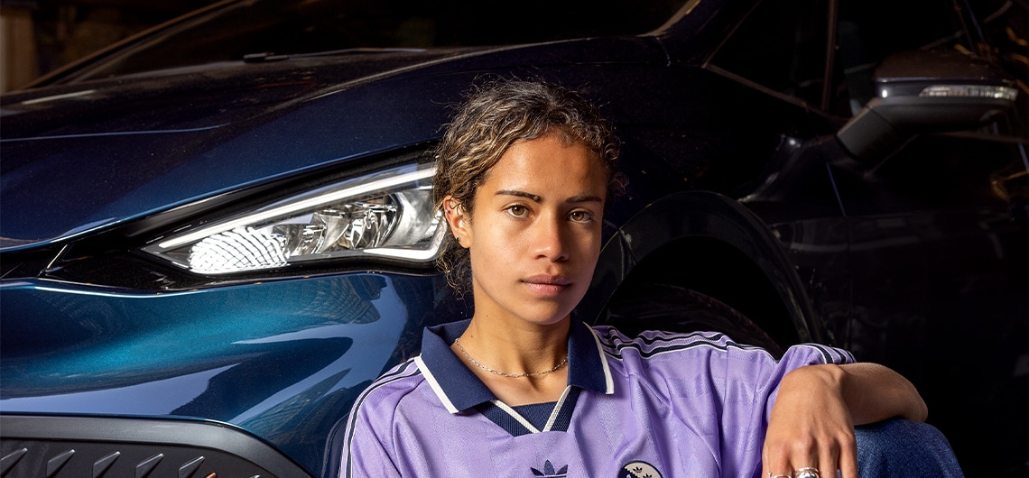 close up of mary fowler, sitting against a cupra vehicle ]